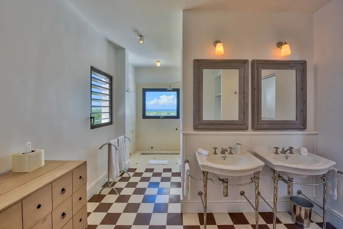 His-and-hers vanities with ocean-view shower — refined comfort in every detail.