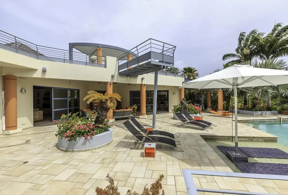 Relax on contemporary loungers under the shade of a white umbrella by the pool.