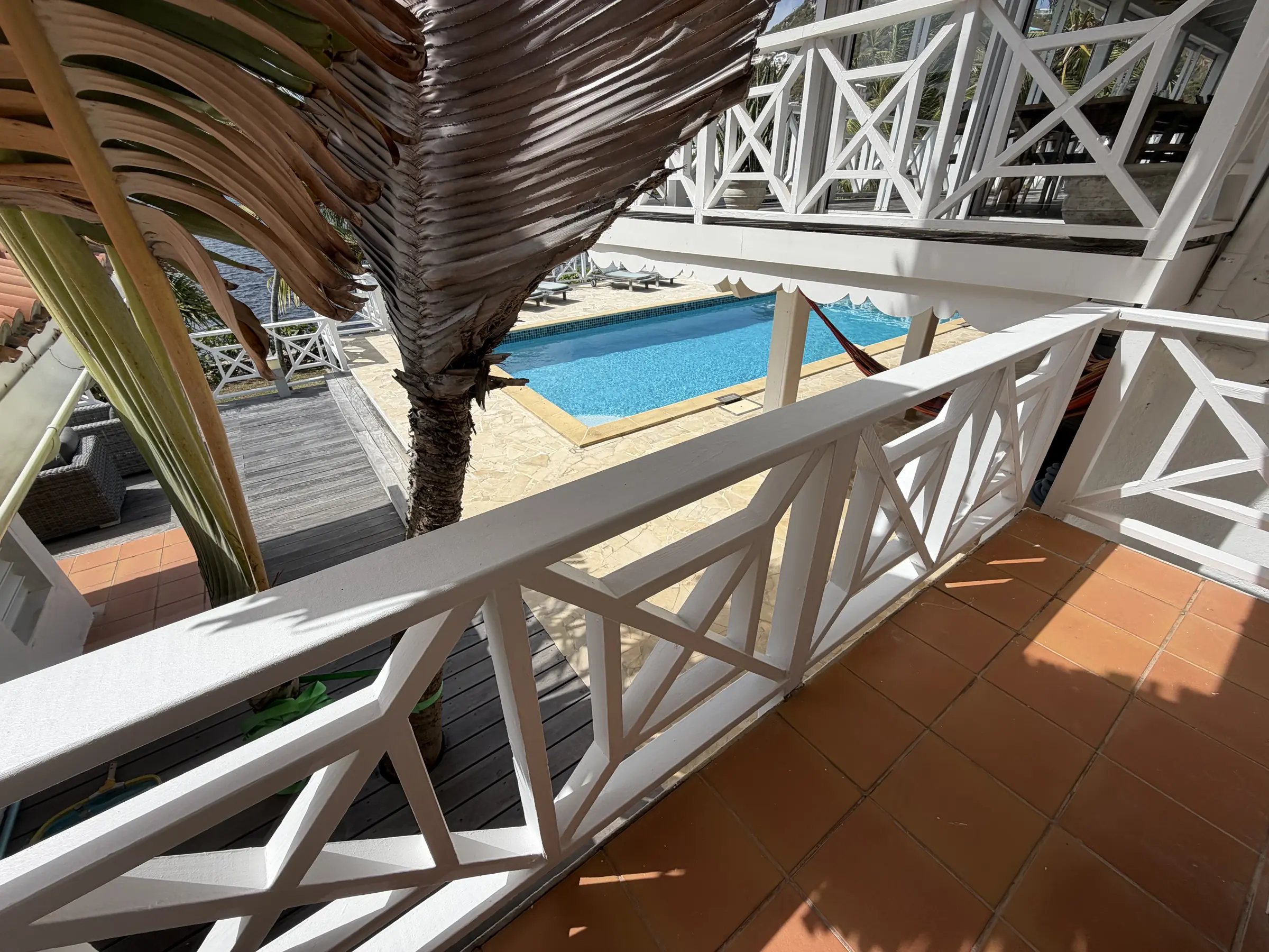 Bedroom 3 balcony looks across the pool and tropical waterfront setting.
