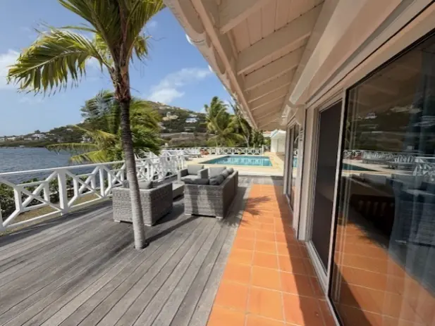 Waterfront terrace with shaded seating and views across Oyster Pond.