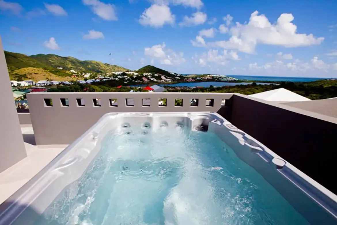 A rooftop hot tub with stunning panoramic view of coastline, mountains, and ocean.
