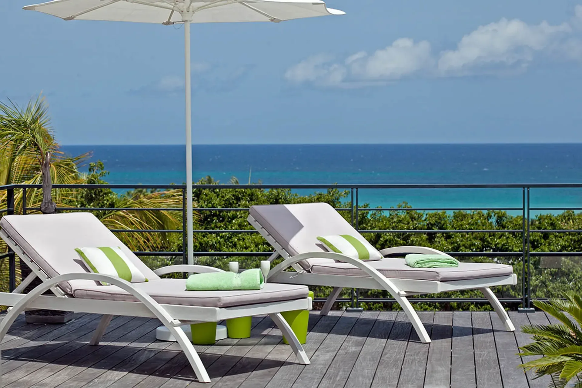 Wooden deck with loungers and white umbrella.