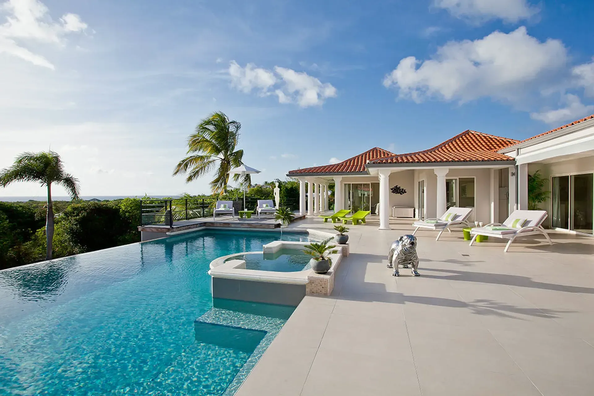 Infinity pool with jacuzzi and Mediterranean villa backdrop.