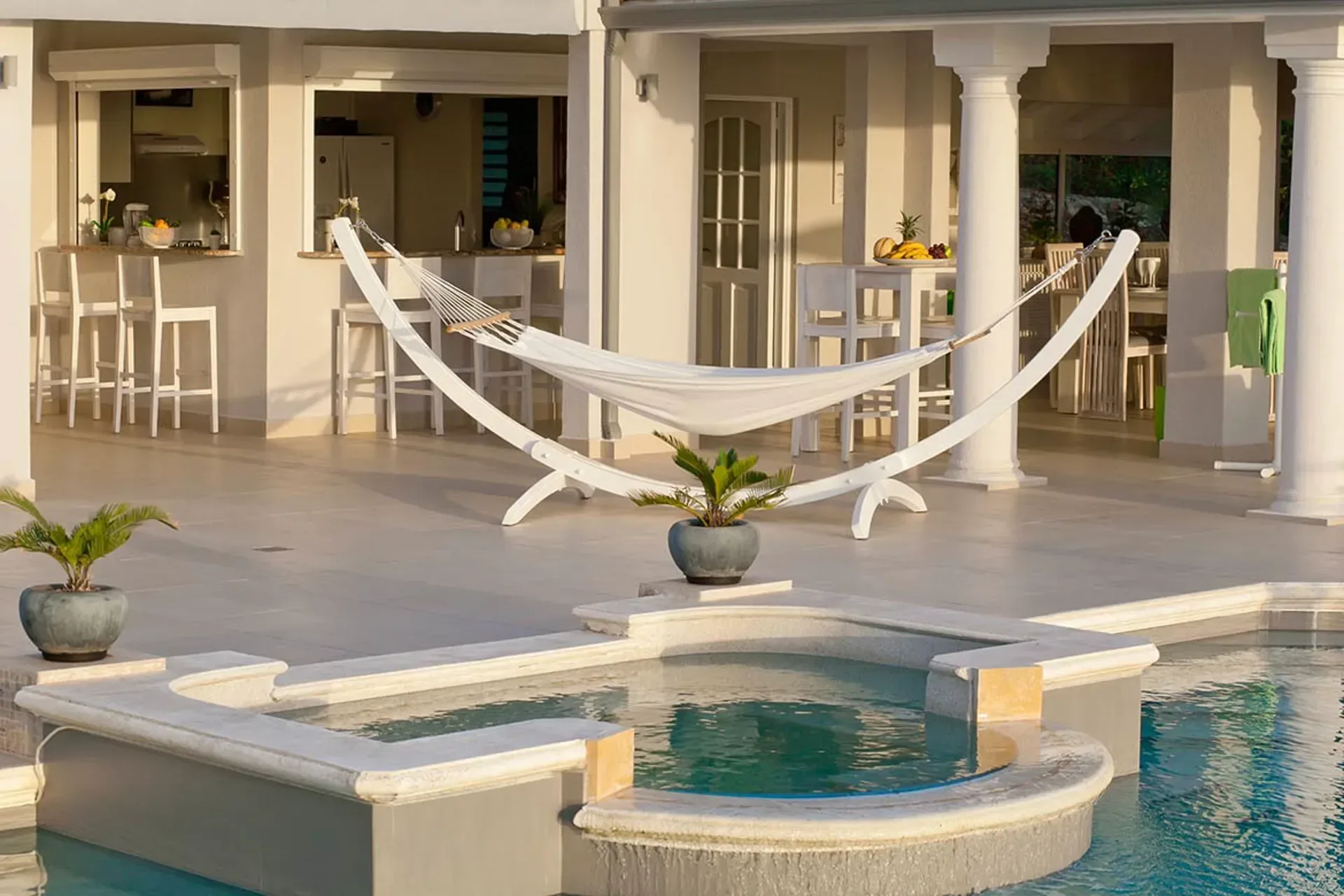 Pool with jacuzzi and covered terrace at dusk.
