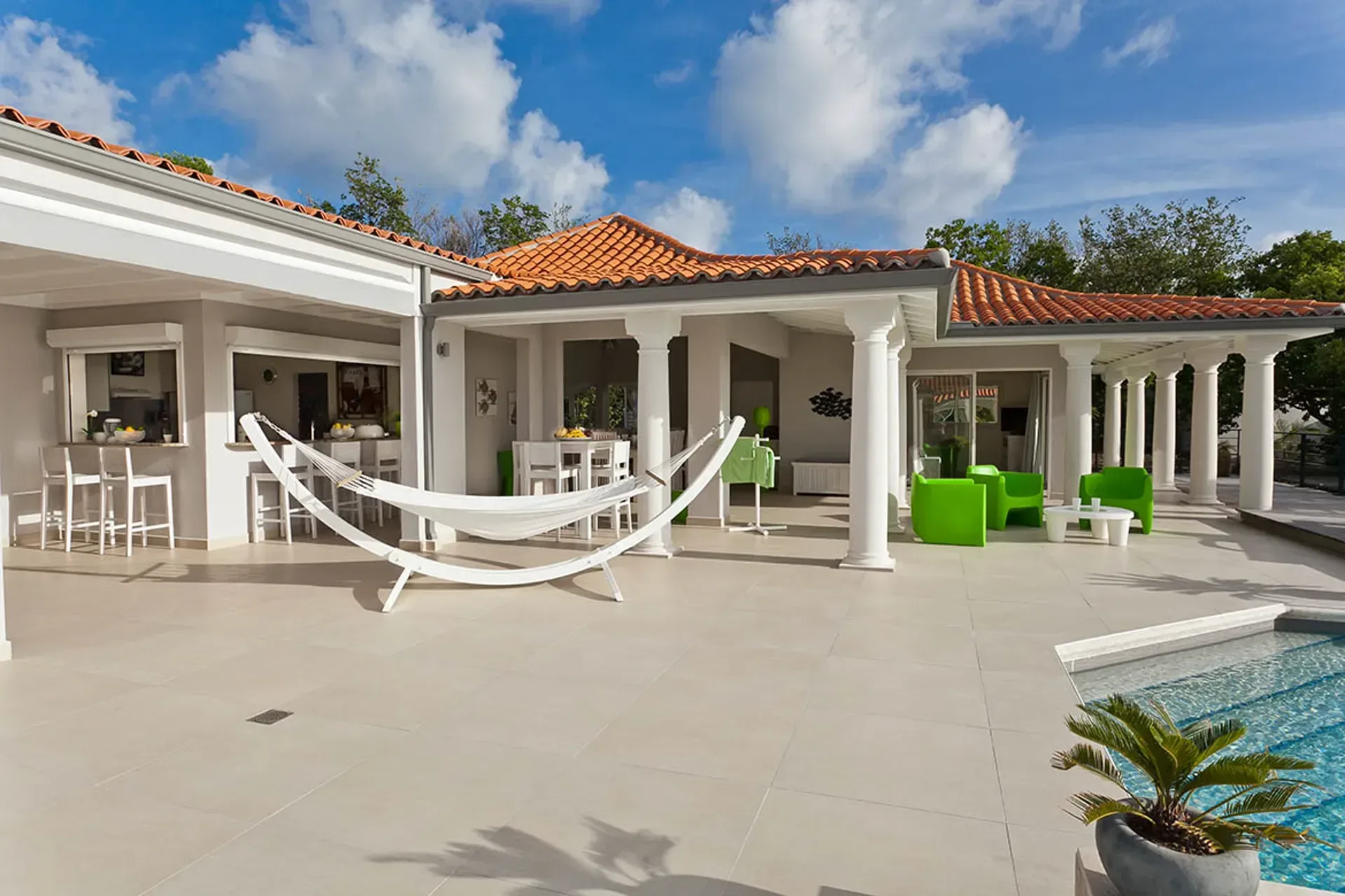 Outdoor terrace with bar area, hammock, and vibrant green seating.