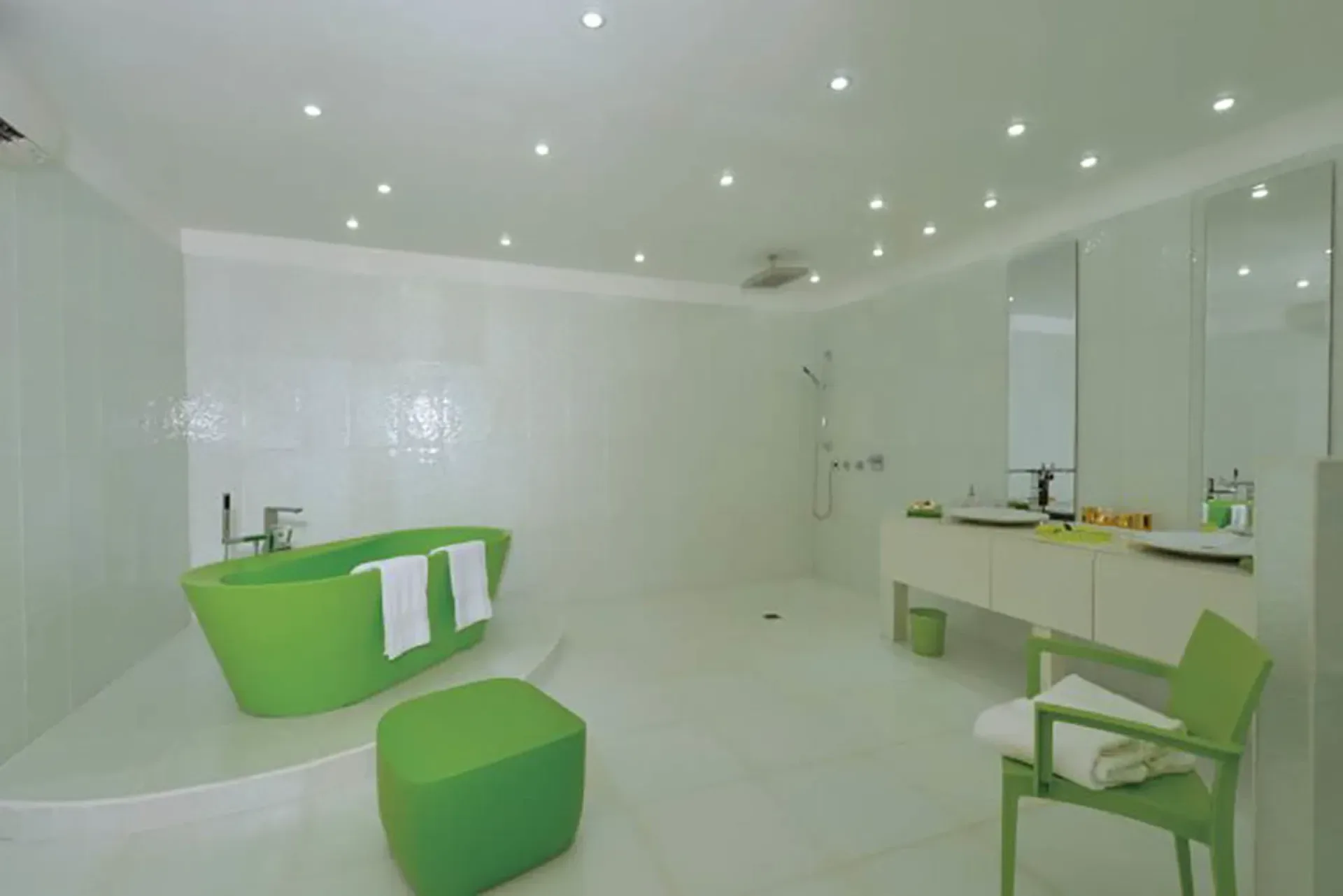 A striking modern bathroom with vibrant lime green freestanding tub, double vanity, and minimalist white design.