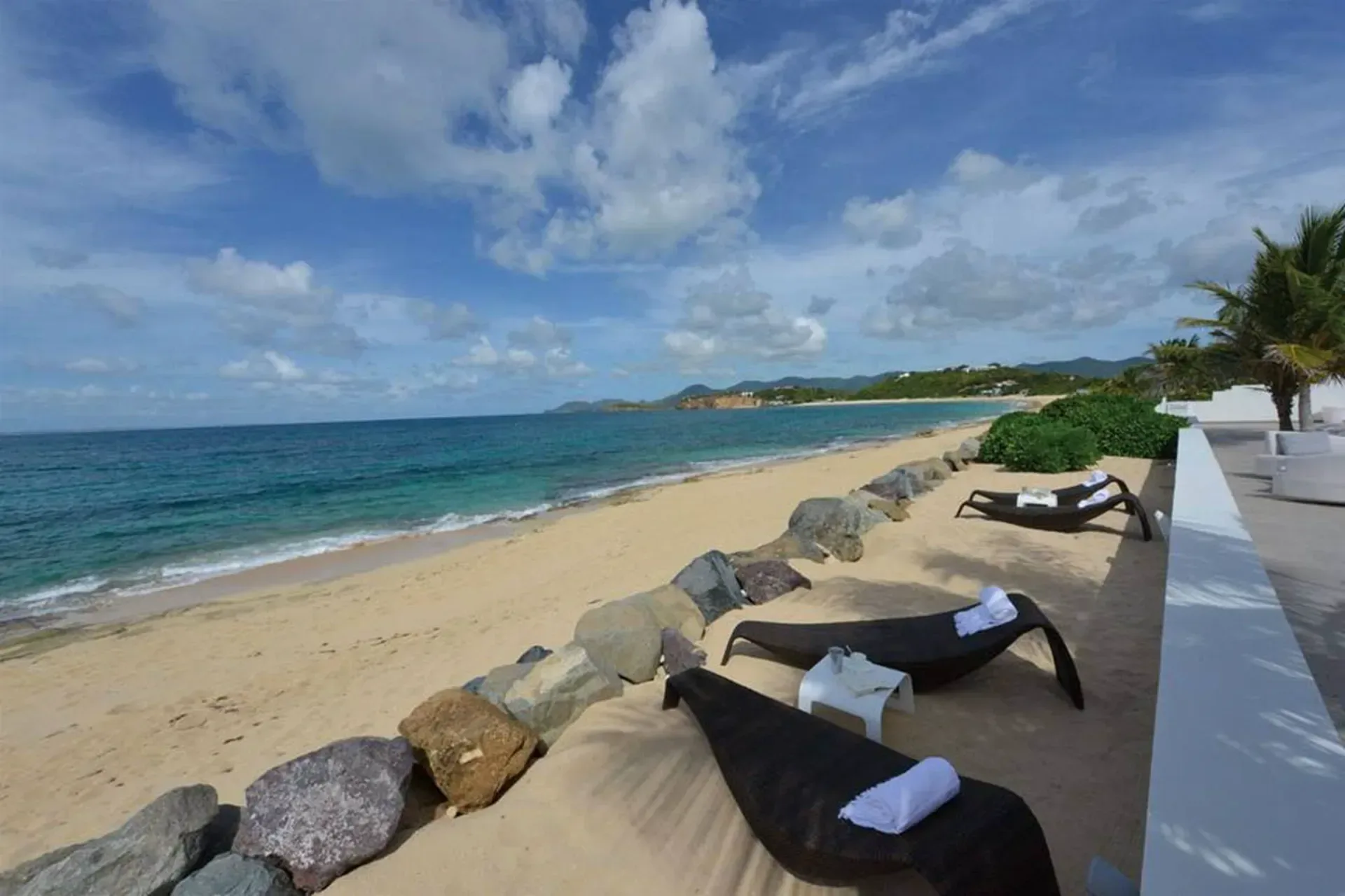 Step directly onto your private beach with comfortable loungers, rocky breakwater, and crystal-clear Caribbean waters.