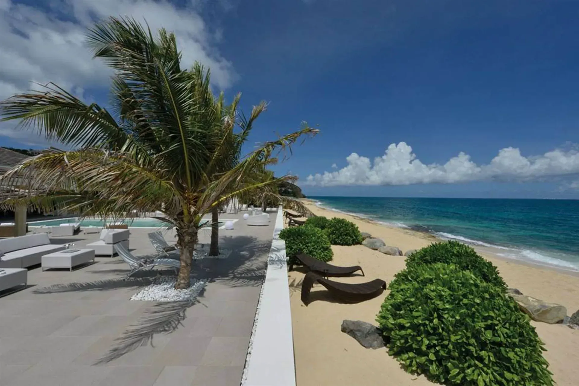 Your private beachfront terrace with modern loungers, swaying palms, and direct access to pristine white sand.