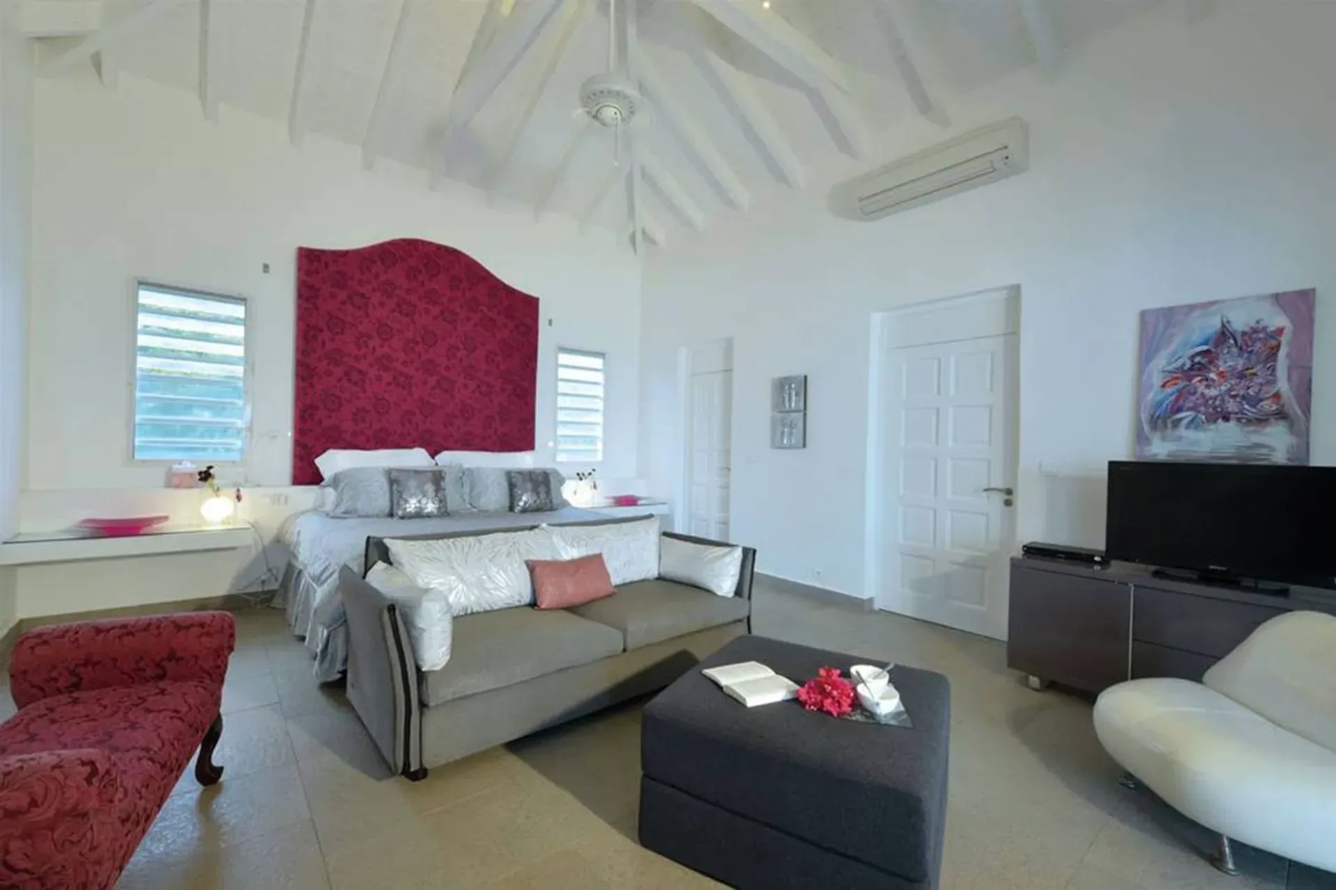 Sleep in style with a dramatic red headboard, vaulted ceilings, and a cozy sitting area in this elegant master suite.