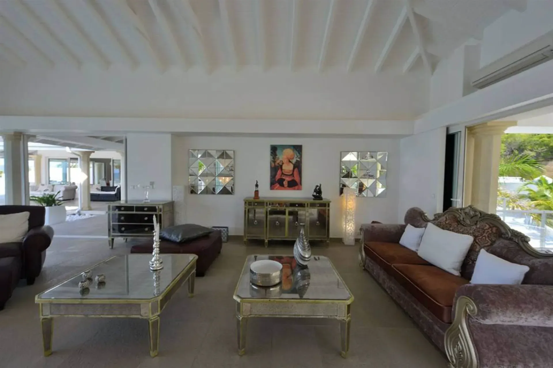 Luxurious living space with ornate velvet seating, mirrored accent tables, and elegant décor that opens to the terrace.