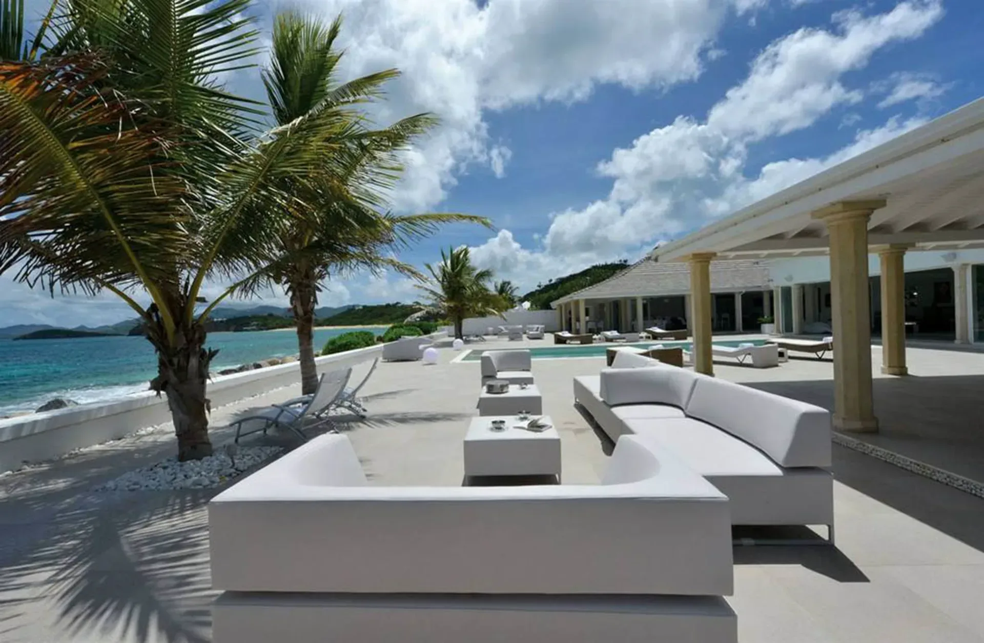 Lounge in style on your covered terrace with plush white seating, tropical palms, and endless ocean views from morning to sunset.