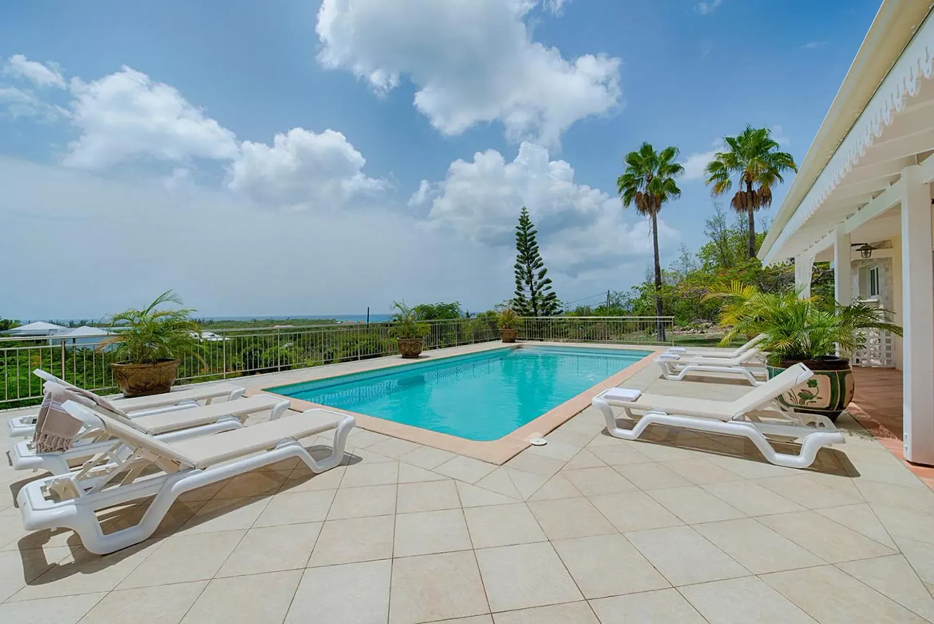 Lounge by the sparkling pool with panoramic views of lush hillsides.