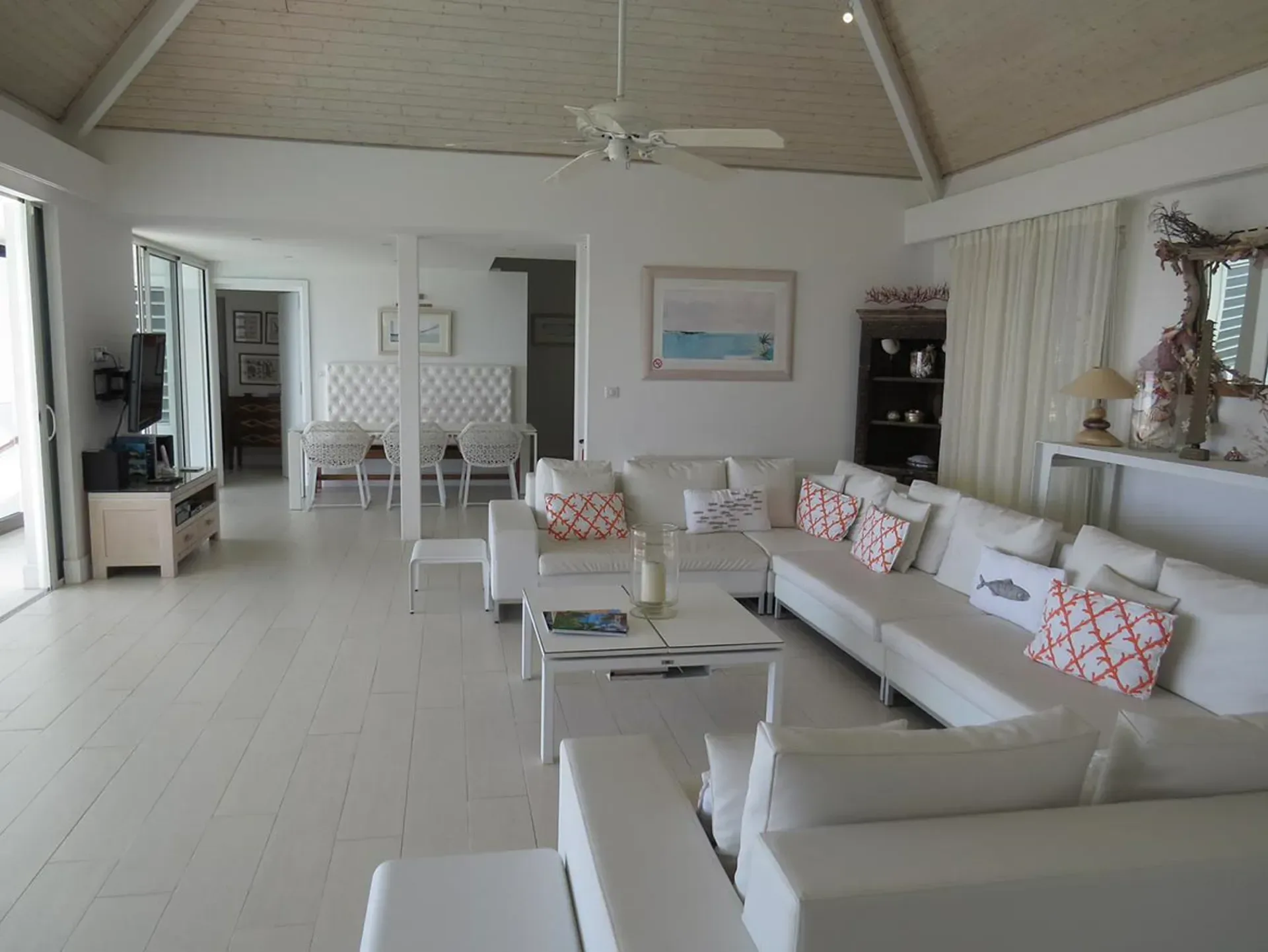 Relax in bright airy coastal elegance with plush white seating and vibrant coral accents.