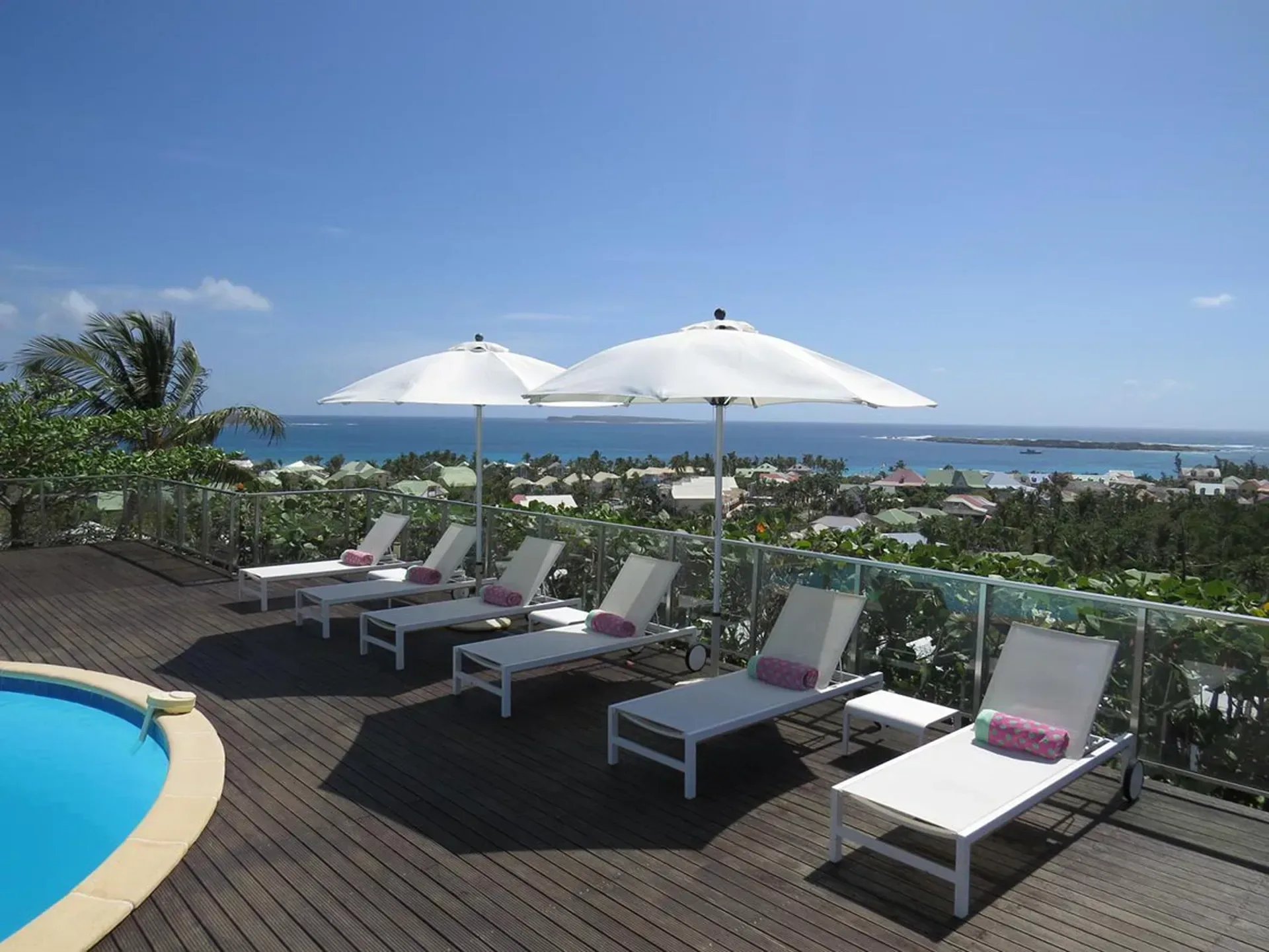 Unwind on elegant poolside loungers with a spacious wooden deck and breathtaking ocean views.
