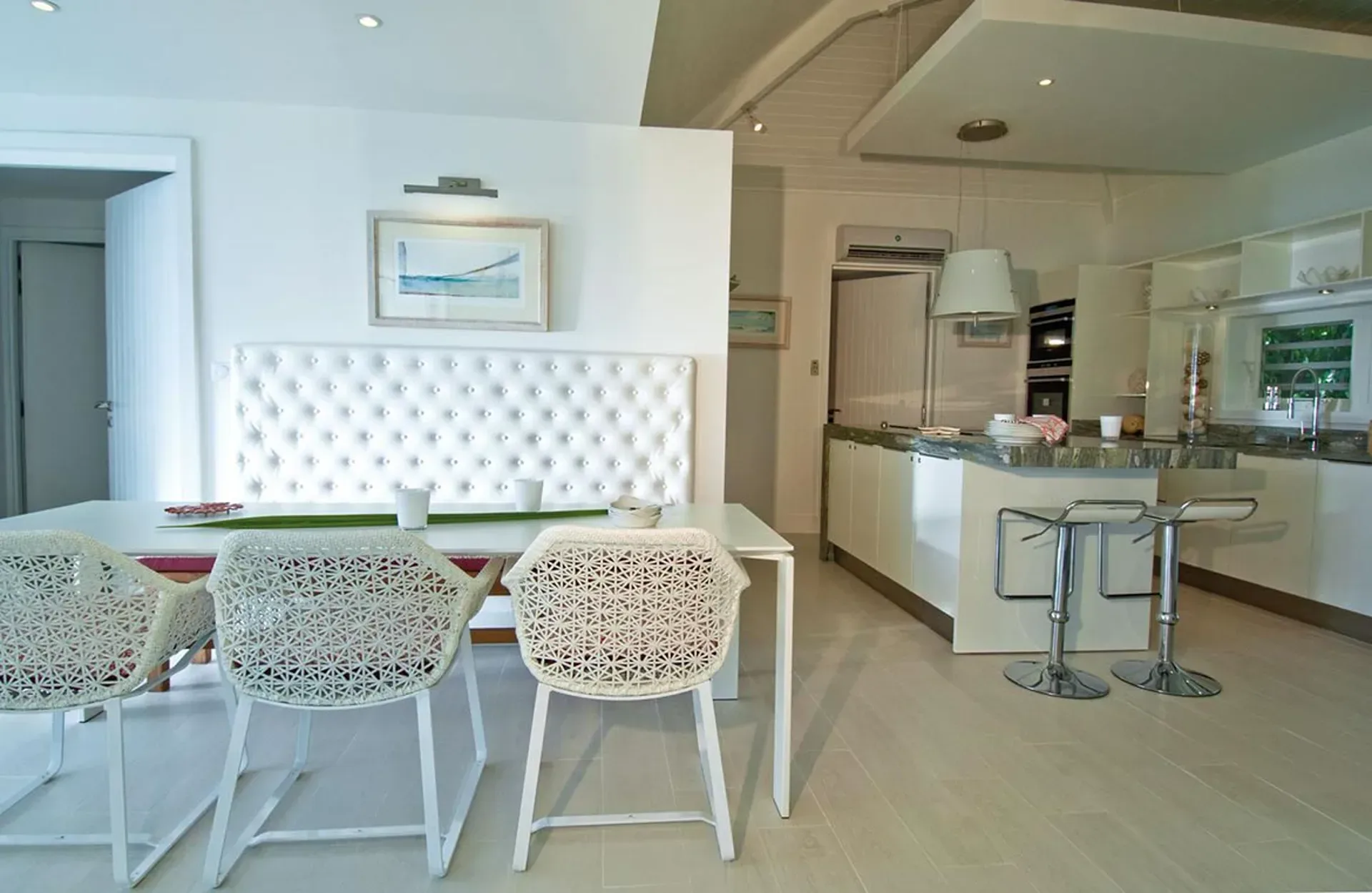 Dine in stylish open-concept elegance with white decor and a sleek breakfast bar.