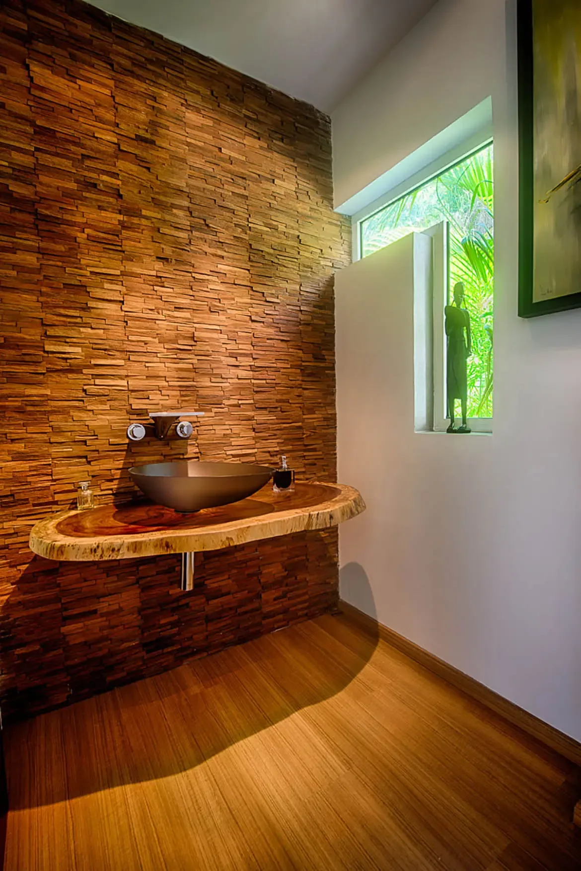 A high-end powder room featuring textured wood-tile accent wall, floating live-edge wood vanity, and sleek dark vessel sink with wall-mounted fixtures.