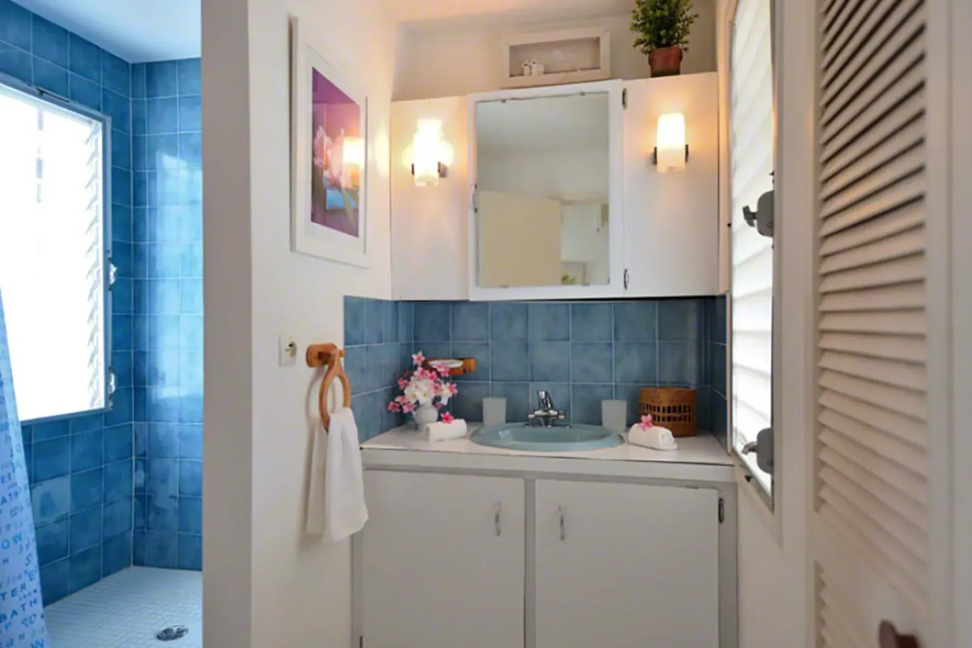 A colorful bathroom with blue tile accents, classic Caribbean vanity, and cheerful décor.