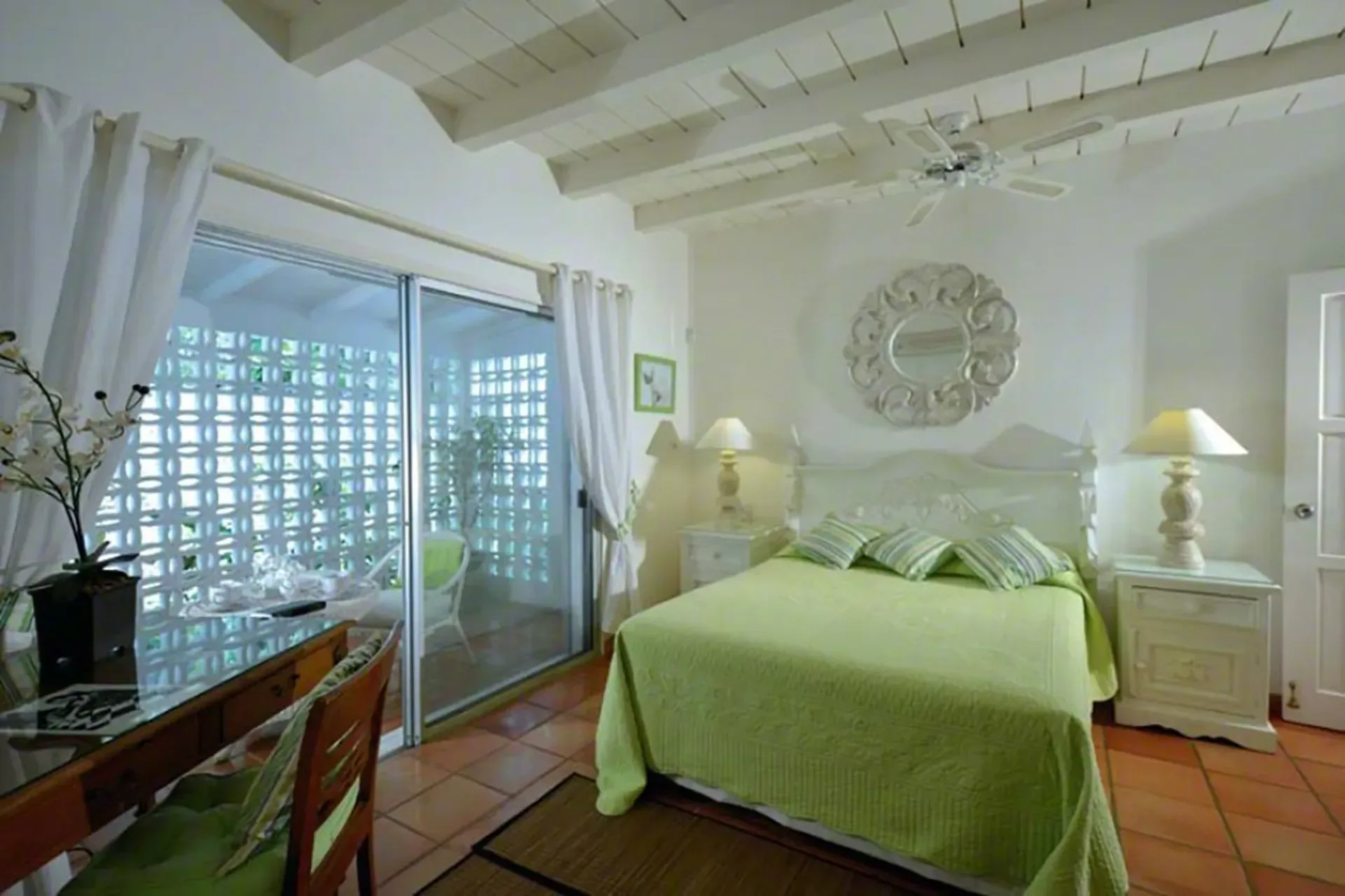 A fresh bedroom with lime green bedding, vaulted ceilings, and private terrace access.