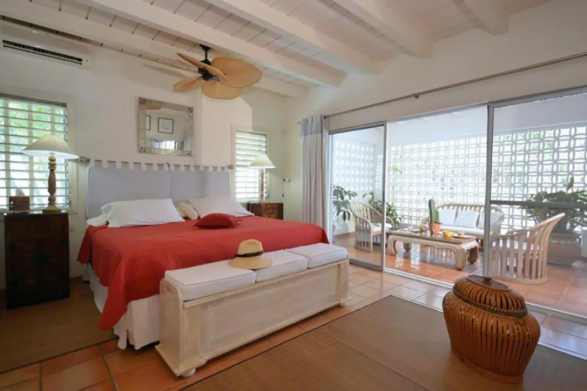 A comfortable bedroom with terrace access and tropical breeze views.