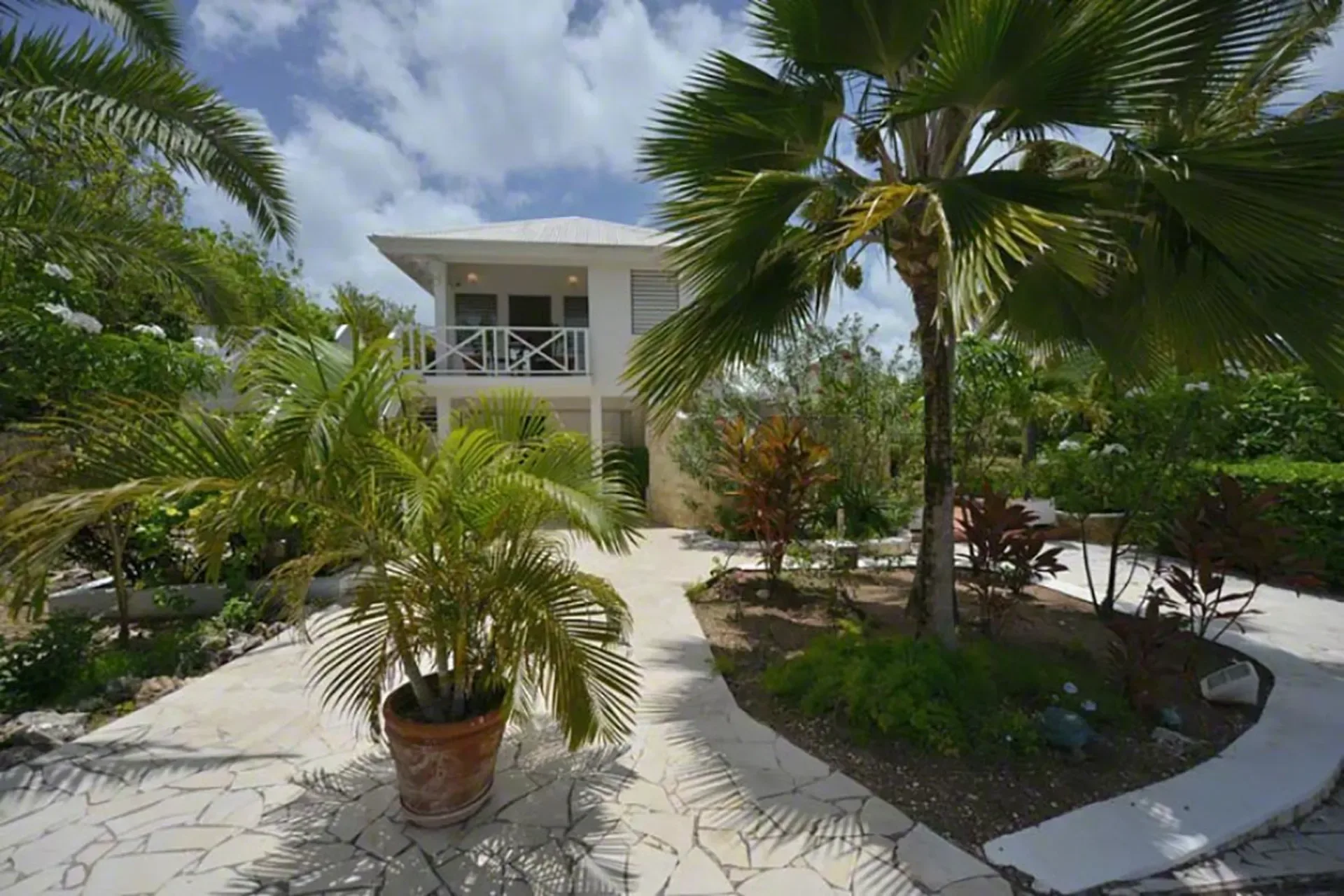 Your private villa entrance with tropical gardens and stone-paved pathways.