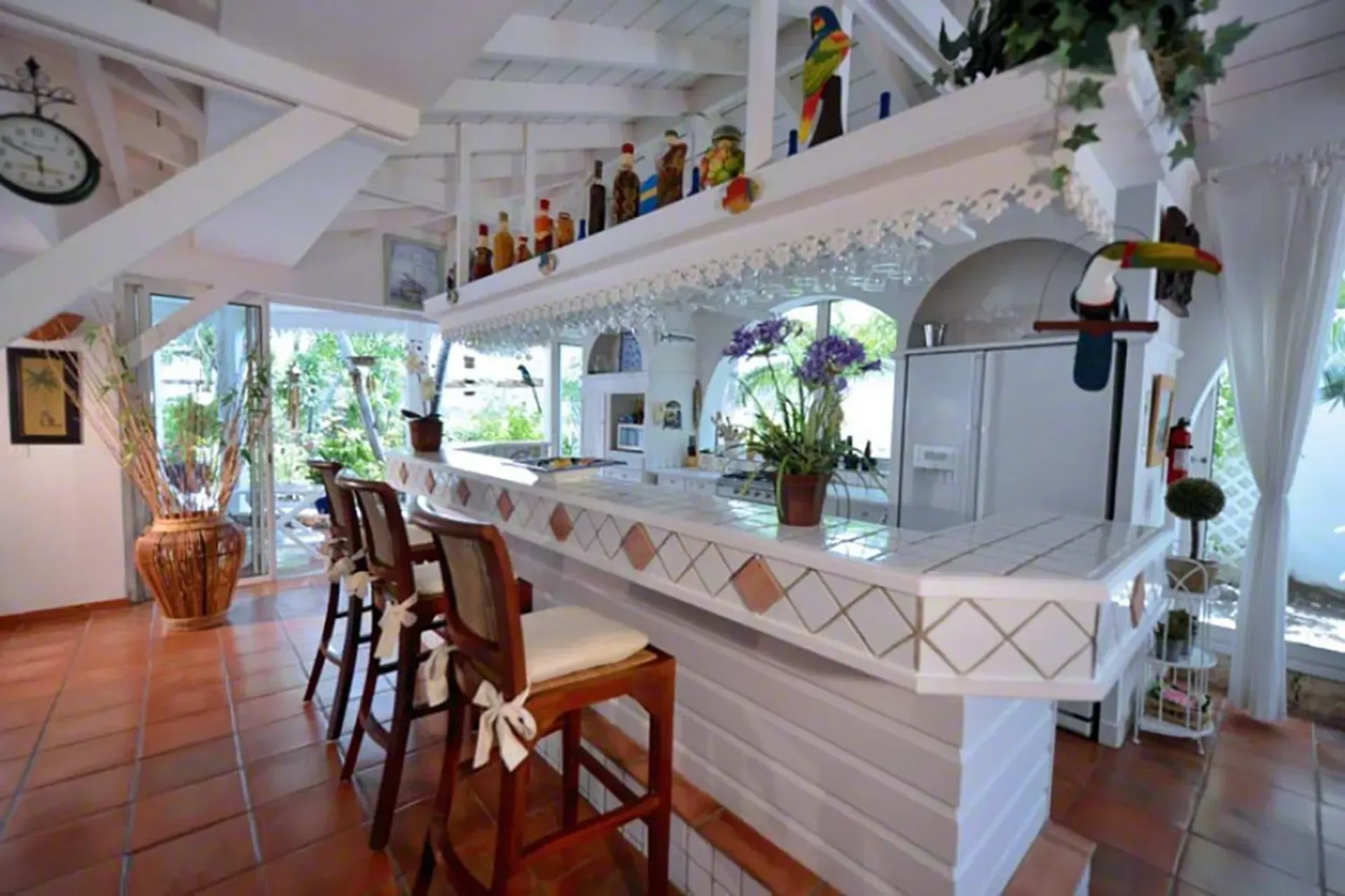 A casual kitchen breakfast bar with wooden stools, tropical décor, and vaulted ceilings.