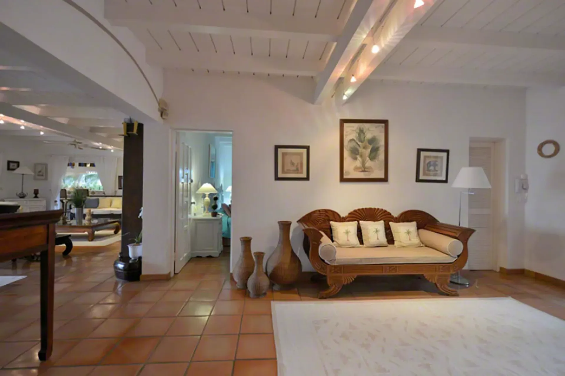 Elegant living space with carved wood sofa, decorative vases, and Mediterranean-tropical style.