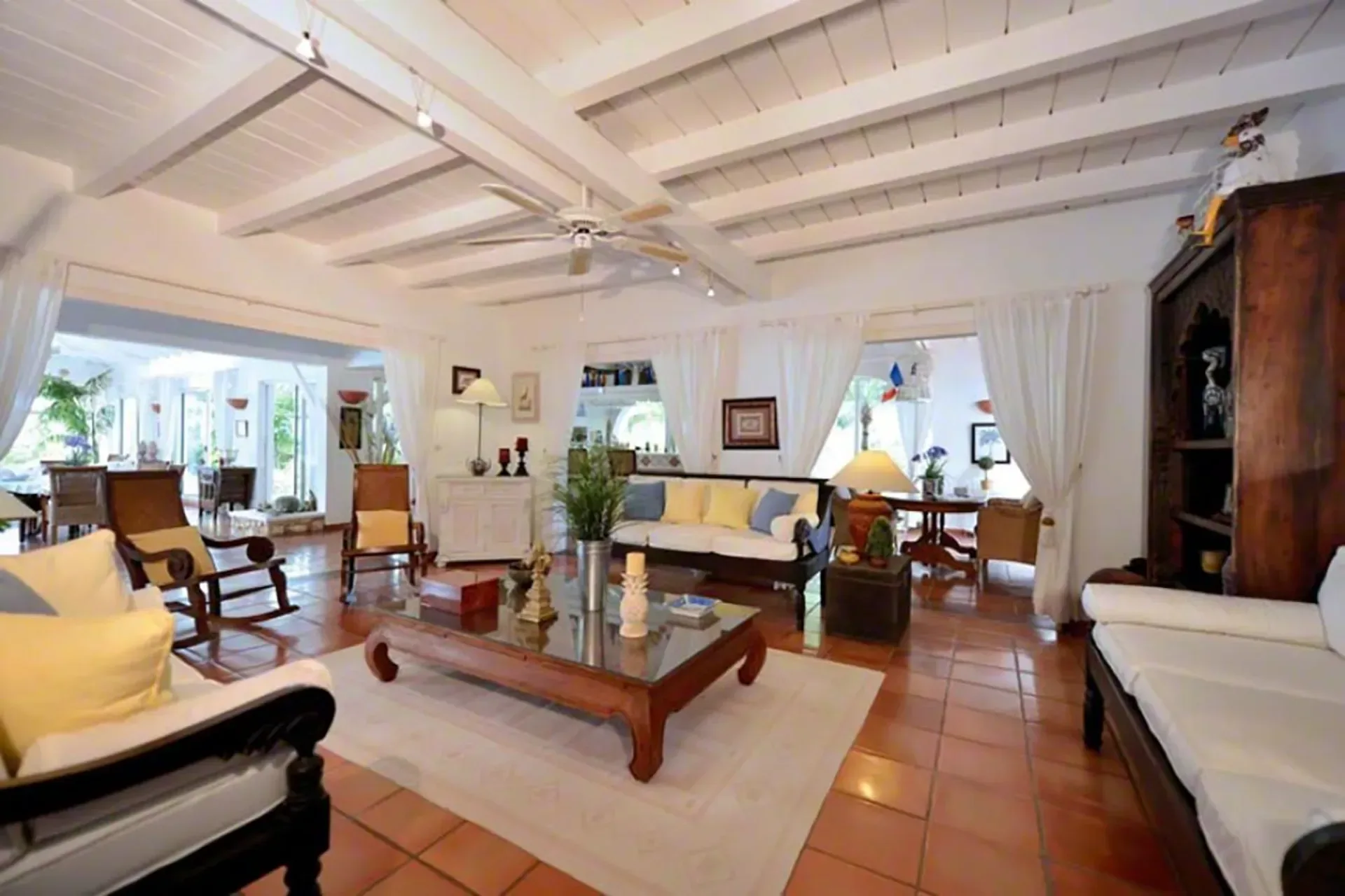 Open living area with exposed beam ceilings, terracotta floors, and views to the dining area.
