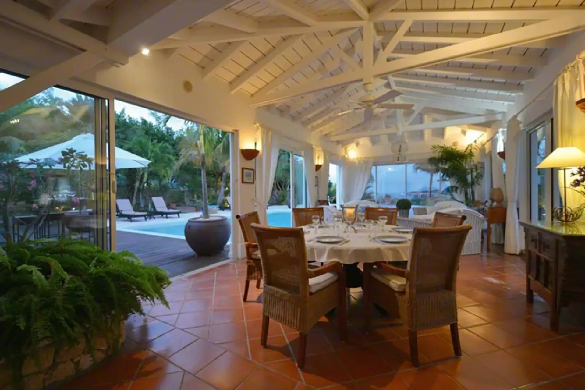 Al fresco dining under vaulted ceilings with pool and garden views.