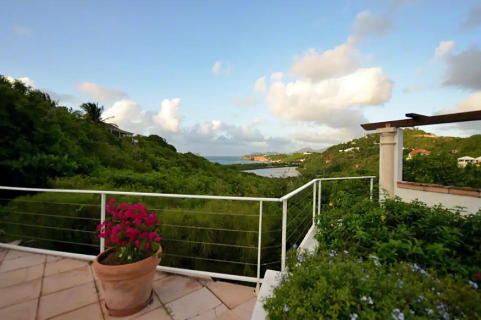 Enjoy panoramic ocean views from your terrace with pink flowers and coastal hills.